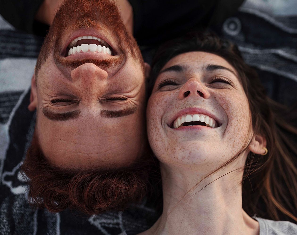 Mann und Frauen liegen nebeneinander auf dem Boden und lachen