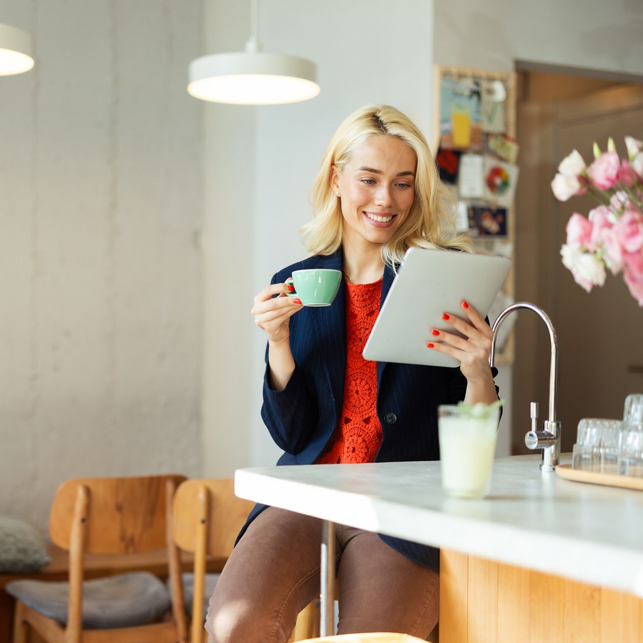 Lächelnde Geschäftsfrau, die am Tablet arbeitet und Kaffee im Café trinkt