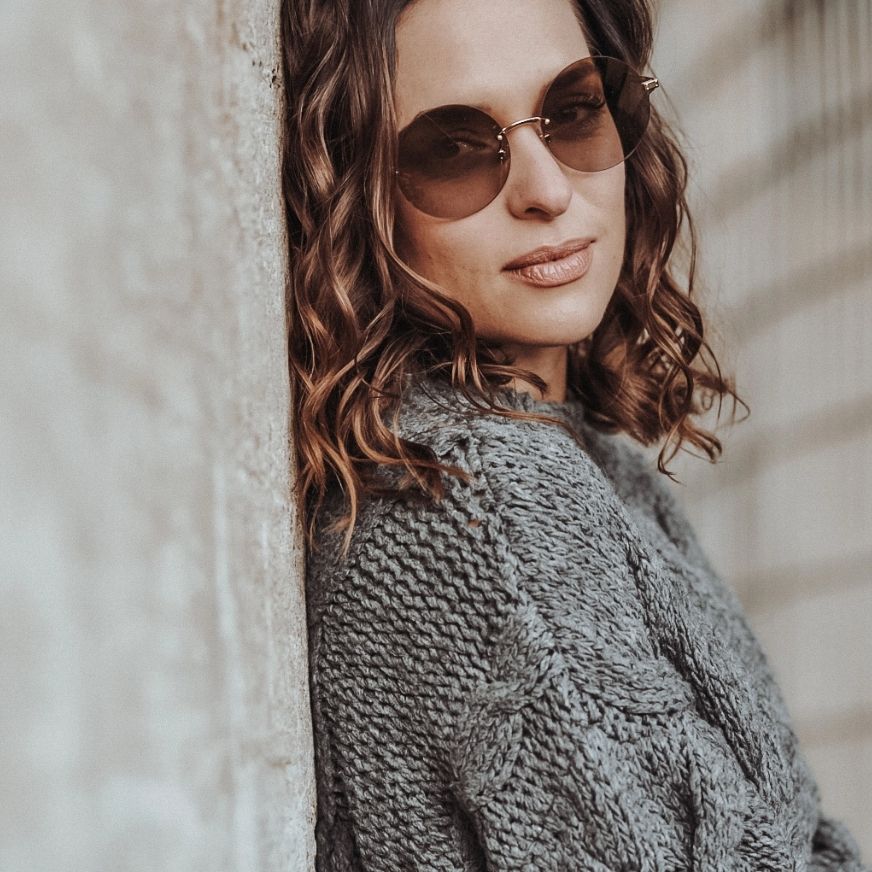Projekt Rottler: Frau mit Sonnenbrille lehnt an einer Wand